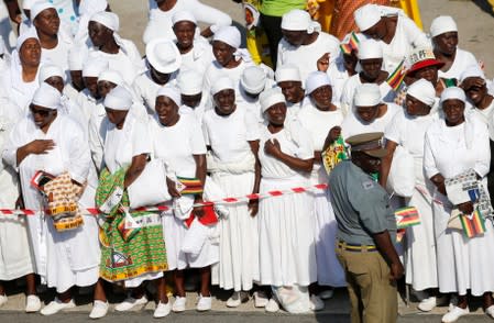 A police officer keeps watch as mourners wait for the arrival of the body of former Zimbabwean President Robert Mugabe to the country, in Harare