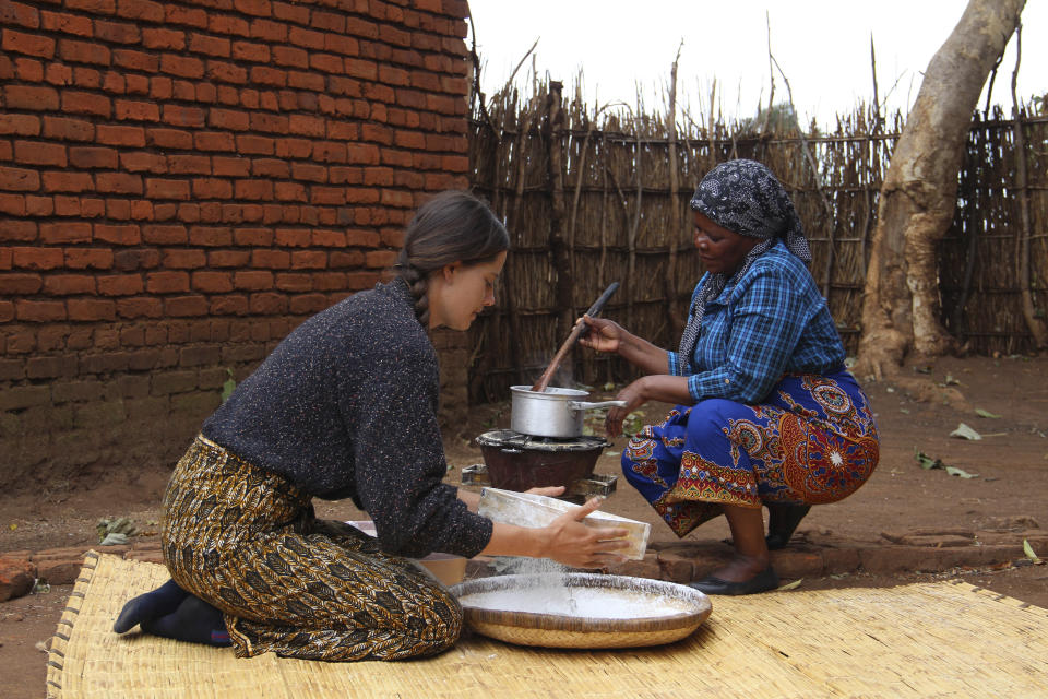 Cameron Beach, left, sieves maize flour as she helps prepare a meal, in Dedza, near Lilongwe, Malawi, Friday, July 23, 2021. Beach, a former Peace Corps volunteer, is living in rural Malawi teaching English at a rural high school where she had been sent by the United States government 18-months before COVID-19 began sweeping the world. (AP Photo/Roy Nkosi)