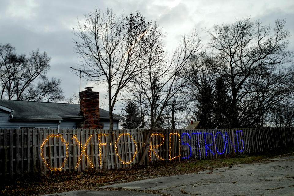 The message "Oxford Strong" lights up a fence along M-24 in Oxford High School's colors, navy blue and gold, on Tuesday, Dec. 7, 2021 in Oxford, Mich., one week after a 15-year-old allegedly killed four classmates, and injured seven others in a shooting inside the northern Oakland County school. (Jake May/The Flint Journal via AP)