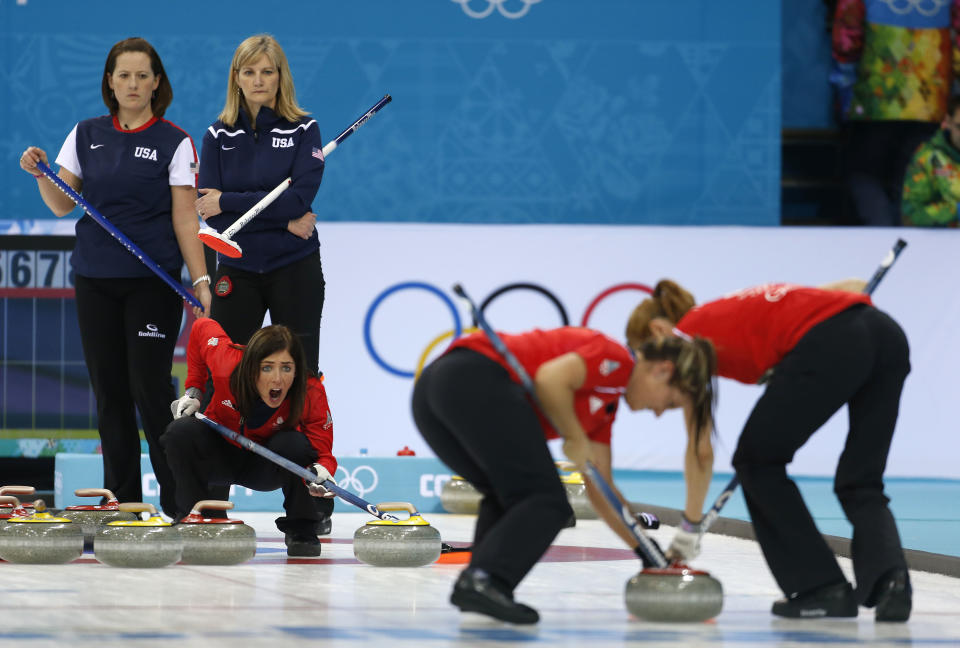 Great Britain's skip Eve Muirhead shouts to the sweepers, Claire Hamilton and Vicki Adams, as they approach the house during women's curling competition against the United States at the 2014 Winter Olympics, Tuesday, Feb. 11, 2014, in Sochi, Russia. Americans Debbie McCormick, left, and Erika Brown look on.(AP Photo/Robert F. Bukaty)