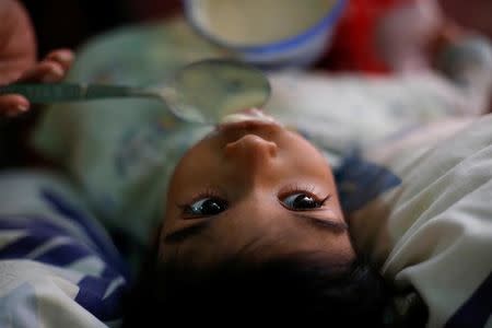 Norymar Torres alimenta a su hijo Leonardo Colmenares de seis años en su casa en Caracas. El niño tiene una enfermedad neurológica y es tratado con anticonvulsivos. REUTERS/Carlos Garcia Rawlins. 16 de enero de 2017.