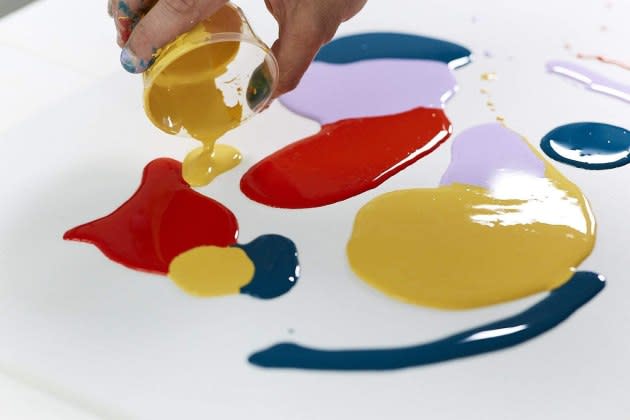 Female Artist Pouring Acrylic Medium For Painting Picture In Fluid