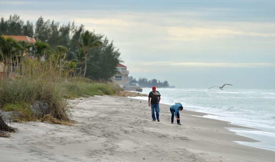 Beachgoers walk on a narrow stretch of beach at Turtle Beach Park on Friday, Dec. 16, 2022.