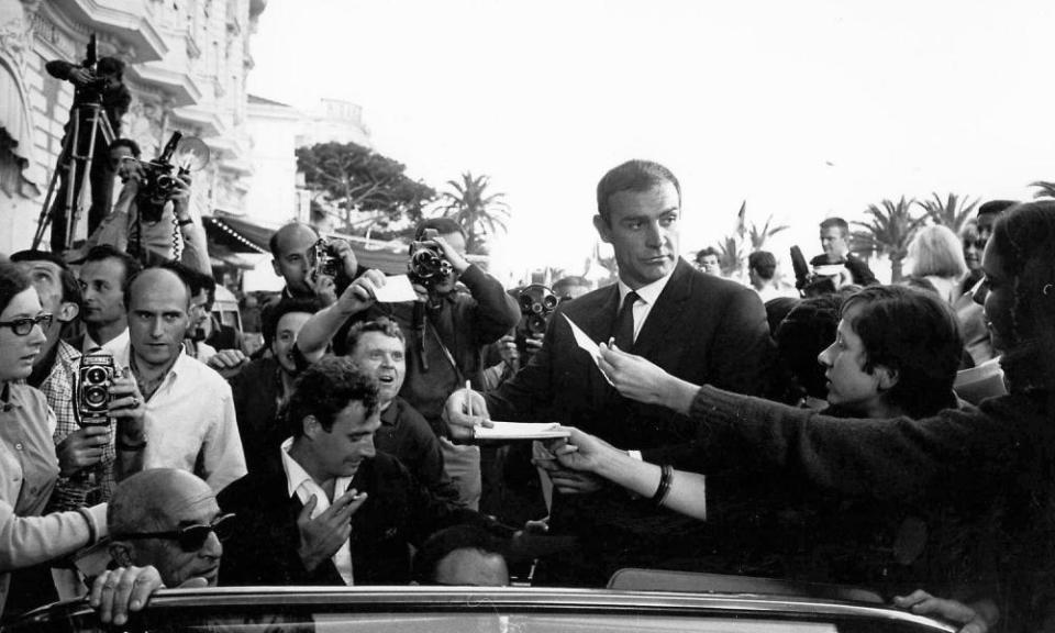 Black and white photograph of Sean Connery signing autographs outdoors at the Cannes film festival