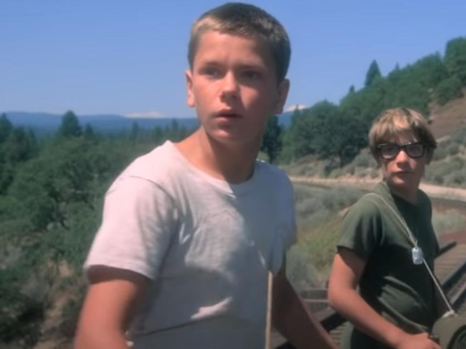 River Phoenix (left) as Chris and Corey Feldman as Teddy notice a train approaching