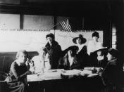 1918: Women sit and stand at a table while enrolling nurses during an influenza epidemic. Graphs post on the wall show mortality rates. (Photo by Hulton Archive/Getty Images)