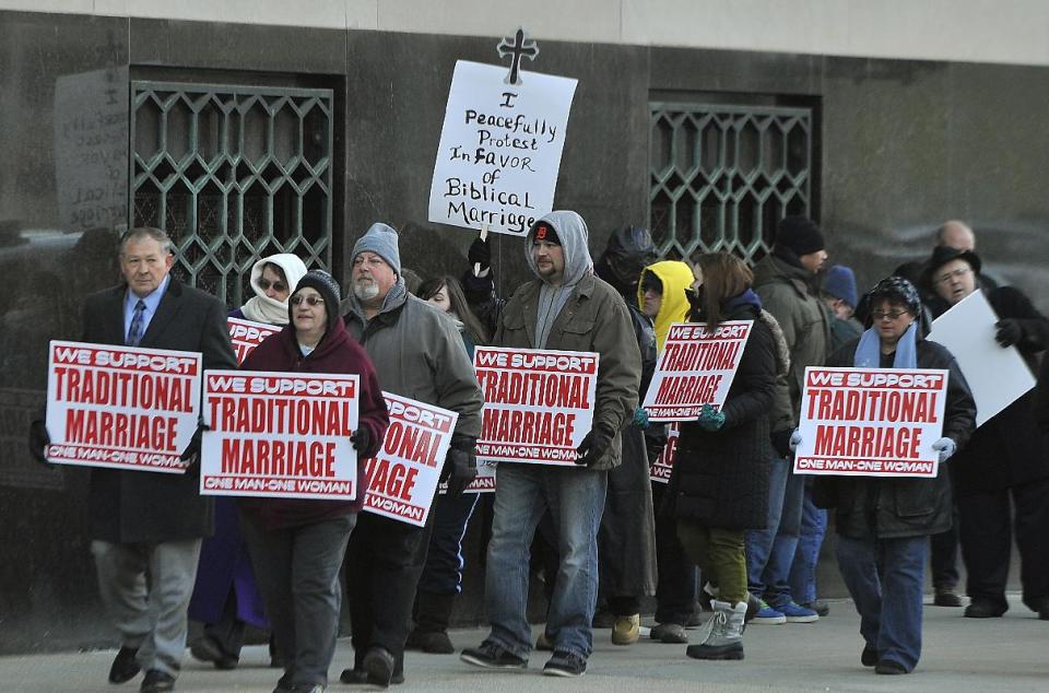 A group opposing same sex marriage demonstrates in front of Federal Court in Detroit, Tuesday, Feb. 25, 2014 before a trial that could overturn Michigan's ban on gay marriage. Gay couples poised for a favorable ruling last fall had lined up for licenses at county offices across Michigan, only to be stunned when U.S. District Judge Bernard Friedman said he wanted to hear testimony from experts. The case began in 2012 when nurses Jayne Rowse, 49, and April DeBoer, 42, of Hazel Park sued to try to upset a Michigan law that bars them from adopting each other's children. But the case became even more significant when Friedman invited them to add the same-sex marriage ban to their lawsuit. They argue that Michigan's constitutional amendment, approved by voters in 2004, violates the U.S. Constitution's Equal Protection Clause, which forbids states from treating people differently under the law. (AP Photo/Detroit News, Daniel Mears) DETROIT FREE PRESS OUT; HUFFINGTON POST OUT