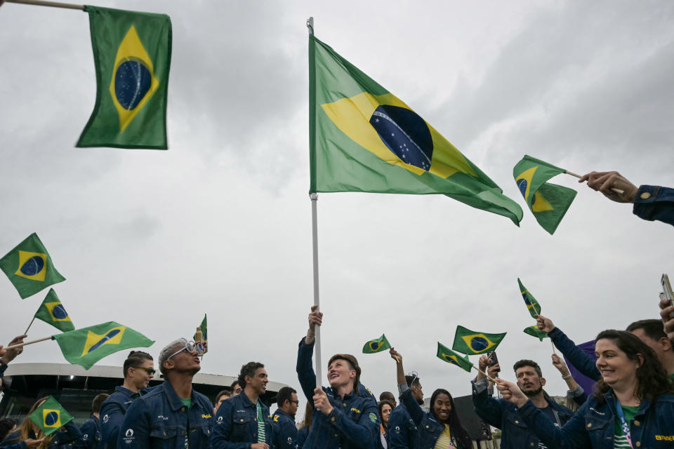 Athletes from the Brazilian delegation wave Brazilian flags while sailing on a boat along the River Seine at the beginning of the opening ceremony of the Paris 2024 Olympic Games, in Paris, on July 26, 2024. / Credit: CARL DE SOUZA/POOL/AFP via Getty Images