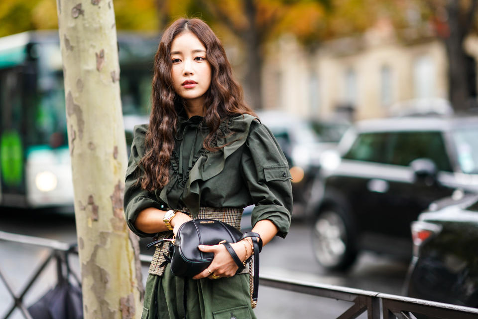 PARIS, FRANCE - OCTOBER 01: A guest wears a long sleeves deep-khaki frilly shirt, khaki  pants, a sand color Prince of Wales check lace-up corset belt, a black Miu Miu bag, outside Miu Miu, during Paris Fashion Week - Womenswear Spring Summer 2020, on October 01, 2019 in Paris, France. (Photo by Edward Berthelot/Getty Images)