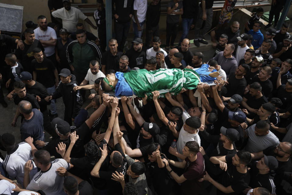 Palestinians carry the body of militant Hamza Kharyoush warped in a Hamas flag in the Nur Shams refugee camp near the city of Tulkarem, in the occupied West Bank Saturday, May 6, 2023 , Saturday, May 6, 2023. Palestinian Health Ministry says Israeli forces have shot dead two Palestinians during a military raid in the occupied West Bank, while a local armed group said the pair were militants. Saturday's deadly raid in the Nur Shams refugee camp near the city of Tulkarem was the latest in Israeli-Palestinian violence that has all but surged since last year. Palestinians said the two dead were 22 years and are members of a local armed group. (AP Photo/Majdi Mohammed)