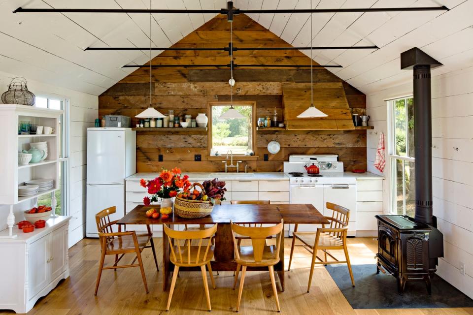 On one side of the tiny house, the great room is home to the dining room and kitchen, which were furnished with vintage pieces of furniture. The walls are covered in wood cladding reclaimed from a barn on the property.