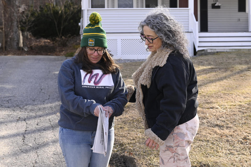 Winsted Citizen subscriber Ruthie Ursone Napoleone, left, opens the first edition of The Winsted Citizen, looking for her father's obituary as reporter Michelle Manafy, right, looks on, Friday, Feb. 3, 2023, in Winsted, Conn. Ursone Napoleone had several connections to the first issue, her workplace and nephew were featured in two separate stories and her father's obituary is in the paper. She stopped Manafy who was delivering papers to ask her if she could have extra copies and said, "I wish my father could read this." At a time that local newspapers are dying at an alarming rate, longtime activist Ralph Nader is helping give birth to one. Nader put up $15,000 to help launch the Winsted Citizen and hired a veteran Connecticut journalist, Andy Thibault, to put it together. (AP Photo/Jessica Hill)