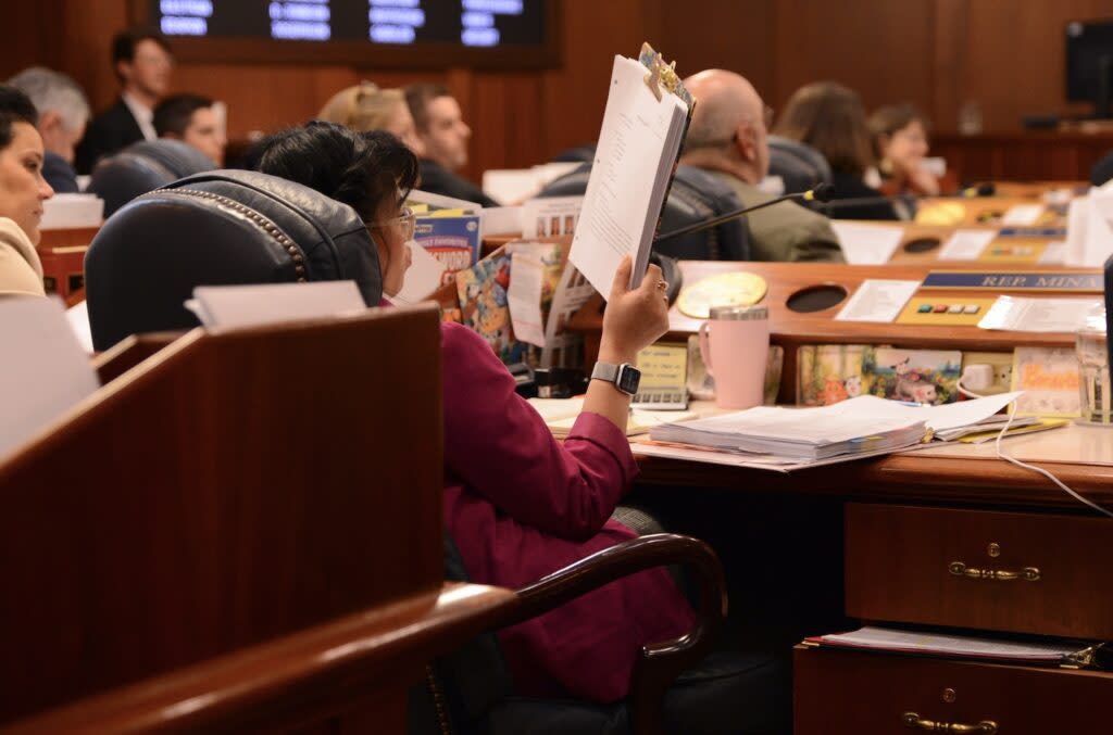 Rep. Genevieve Mina, D-Anchorage, stares at a pile stack of budget amendments on Tuesday, April 9, 2024. (Photo by James Brooks/Alaska Beacon)