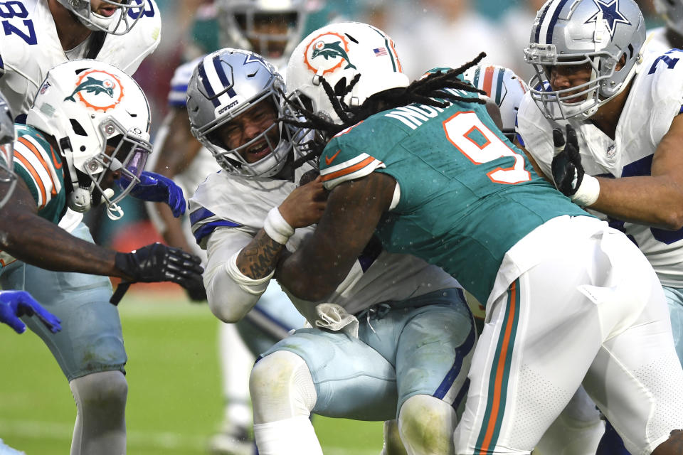 Miami Dolphins linebacker Melvin Ingram (9) tackles Dallas Cowboys quarterback Dak Prescott, center, during the first half of an NFL football game, Sunday, Dec. 24, 2023, in Miami Gardens, Fla. (AP Photo/Michael Laughlin)