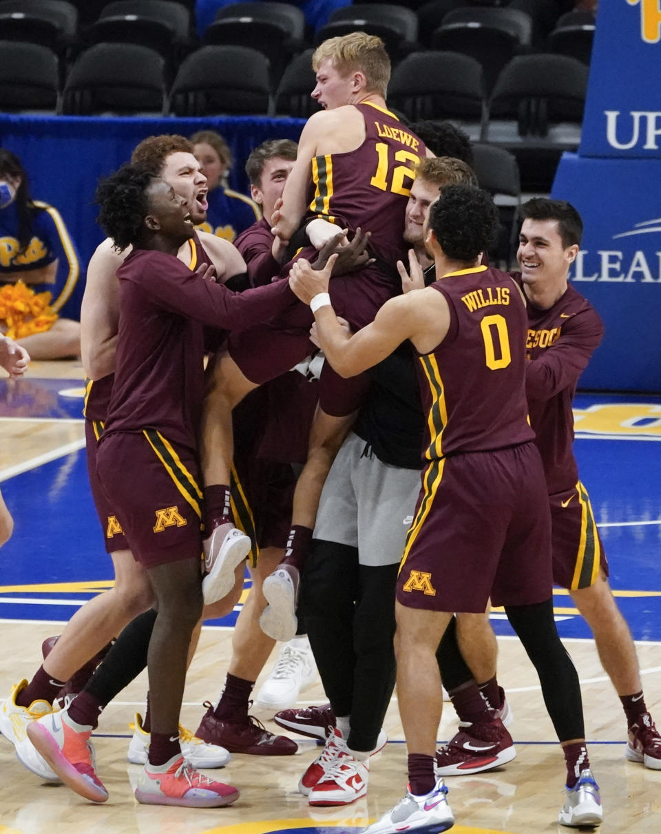 Minnesota's Luke Loewe (12) is hoisted by teammates after Minnesota defeated Pittsburgh 54-53 in an NCAA college basketball game, Tuesday, Nov. 30, 2021, in Pittsburgh. Loewe scored the go-ahead basket in the closing seconds. (AP Photo/Keith Srakocic)