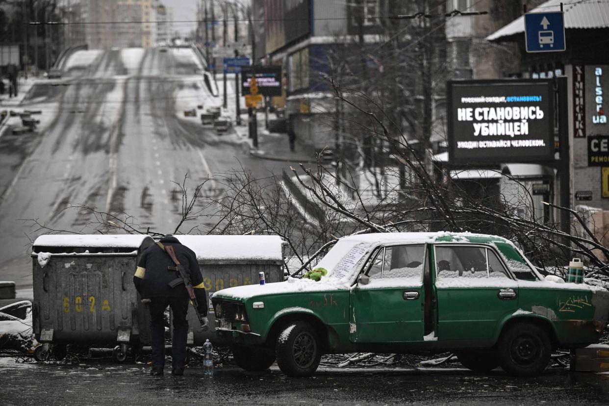 An armed man stands at a road block in downtown Kyiv on March 1, 2022. Ukrainian President described Russian shelling of his country's second city as a war crime and said defending the capital from Moscow's army was a top priority.