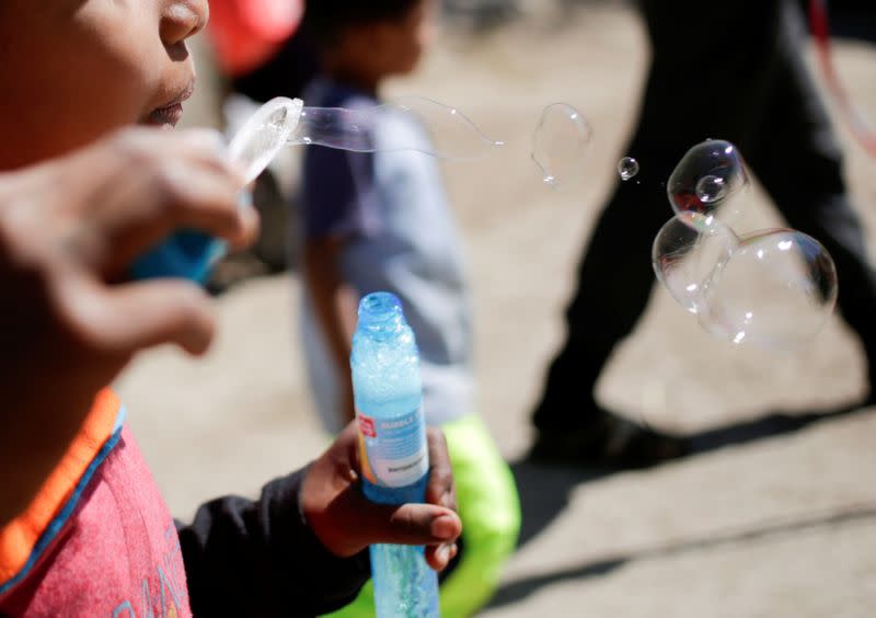 A migrant boy, who is an asylum seeker sent back to Mexico from the U.S. under the "Remain in Mexico" program officially named Migrant Protection Protocols (MPP), blows soap bubbles at provisional campsite near the Rio Bravo in Matamoros