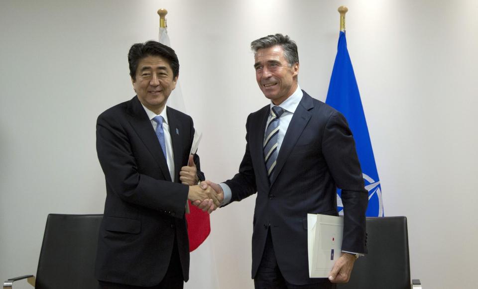 Japan's Prime Minister Shinzo Abe, left, and NATO Secretary General Anders Fogh Rasmussen, right, shake hands after signing a cooperation agreement at NATO headquarters in Brussels on Tuesday, May 6, 2014. Abe will, in a two-day visit, meet with NATO, EU and Belgian officials. (AP Photo/Virginia Mayo, Pool)