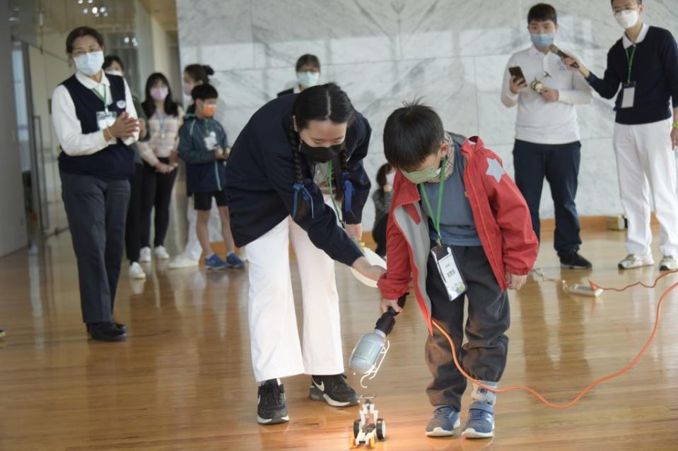 學童親手組裝太陽能車，用燈光照射，體驗光能發電驅動車輛前進的樂趣。（記者彭新茹攝）