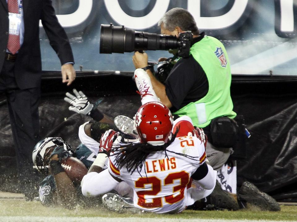 Philadelphia Eagles' LeSean McCoy (25) and Kansas City Chiefs' Kendrick Lewis (23) roll into a photographer on the sidelines after McCoy scored a touchdown during the fourth quarter of their NFL football game in Philadelphia, Pennsylvania, September 19, 2013. Kansas City won 26-16. REUTERS/Tom Mihalek (UNITED STATES - Tags: SPORT FOOTBALL)