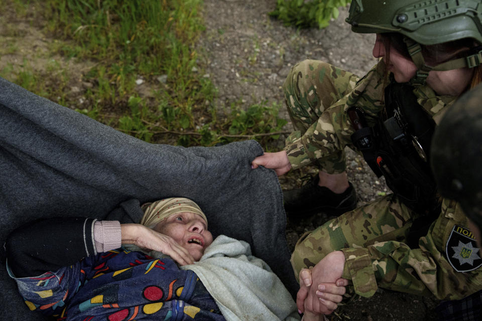 A police officer speaks to en elderly woman after a Russian airstrike during evacuation in Vovchansk, Ukraine, on Saturday, May 11, 2024. (AP Photo/Evgeniy Maloletka)