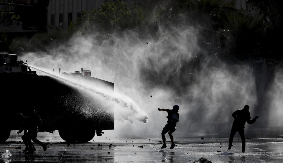 Manifestantes se enfrentan con la policía, que les rocía agua, durante una protesta contra el gobierno en Santiago de Chile el martes 5 de noviembre de 2019. (AP Foto/Esteban Felix)