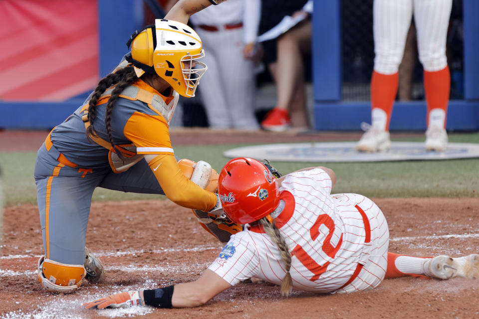 Tennessee's Giulia Koutsoyanopulos, left, tags out Oklahoma State's Micaela Wark (12) at home plate during the fourth inning of an NCAA softball Women's College World Series game, Sunday, June 4, 2023, in Oklahoma City. (AP Photo/Nate Billings)