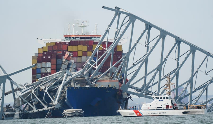 A Coast Guard cutter passes a cargo ship that is stuck under the part of the structure of the Francis Scott Key Bridge after the ship his the bridge Tuesday, March 26, 2024, in Baltimore, Md. (AP Photo/Steve Helber)