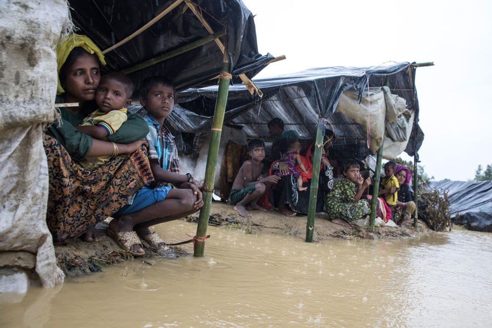 <p>Refugees shelter from a downpour as the monsoon rains create massive challenges for the displaced Rohingya on September 17 in Kutupalong, Cox’s Bazar, Bangladesh. The family of four is still waiting for a tent. (Photograph by Paula Bronstein/Getty Images) </p>