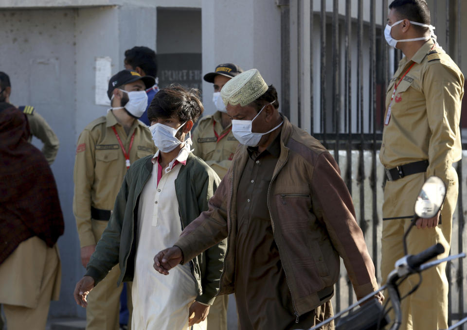 People and private guards wear masks while gather outside a hospital, where victims of toxic gas leak, are treated in Kamari neighborhood of Karachi, Pakistan, Monday, Feb. 17, 2020. A toxic gas leak killed five people and sickened dozens of others in a coastal residential area in Pakistan's port city of Karachi, police said Monday. The source of the leak, which occurred on Sunday night, and the type of gas that had leaked were not immediately known. There was no suspicion of sabotage. (AP Photo/Fareed Khan)