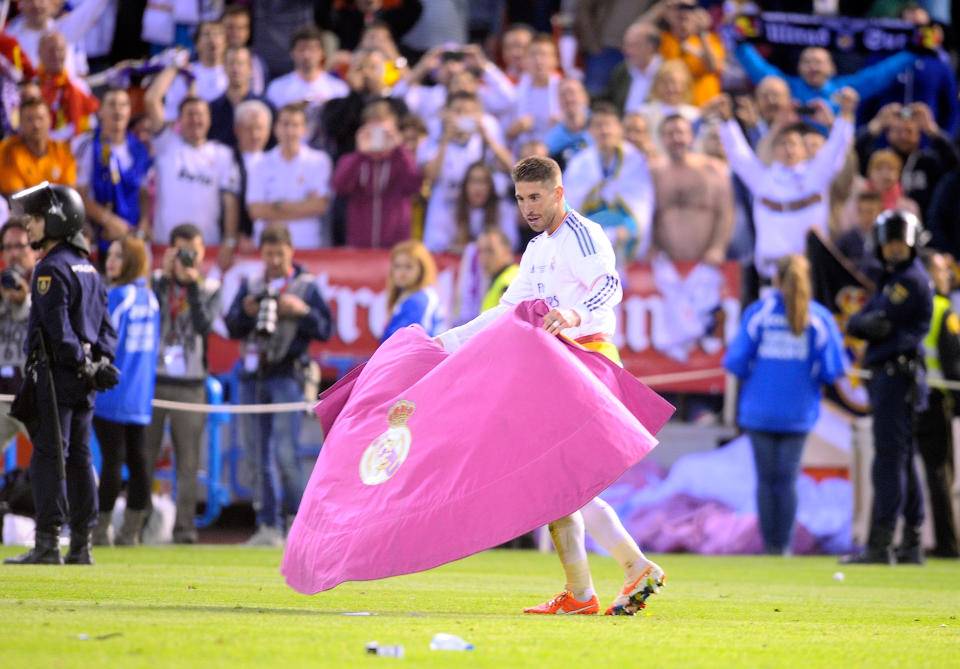 Real's Sergio Ramos plays with a bullfighting cape at the end of the final of the Copa del Rey between FC Barcelona and Real Madrid at the Mestalla stadium in Valencia, Spain, Wednesday, April 16, 2014. Real defeated Barcelona 2-1. (AP Photo/Manu Fernandez)