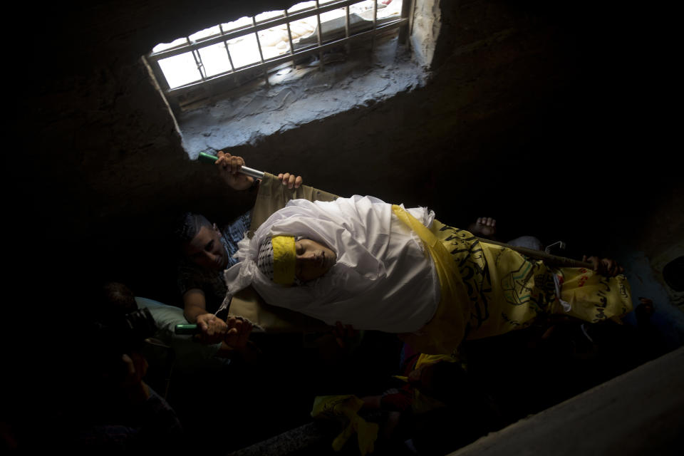 Palestinian carry the body of Mohammed Abbas, 21, who was killed by Israeli troops during Friday's protest at the Gaza Strip's border with Israel, into the family home during his funeral in Gaza City, Saturday, Oct. 13, 2018. (AP Photo/Khalil Hamra)