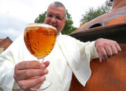 Norbertine Father Karel poses with a Grimbergen beer, symbolised by a phoenix, in the courtyard of the Belgian Abbey of Grimbergen before announcing that the monks will return to brewing after a break of two centuries, in Grimbergen, Belgium May 21, 2019. REUTERS/Yves Herman