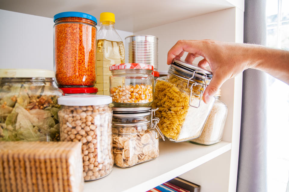 A Man Takes or Places Glass Jars Filled With Legumes From A Shelf In The Pantry