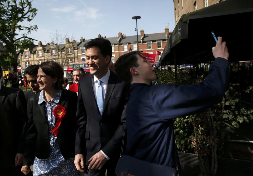 A boy tries to capture a selfie with Britain's opposition Labour Party leader Ed Miliband as he walks back to his bus during a campaign visit to north London, April 16, 2015. REUTERS/Suzanne Plunkett