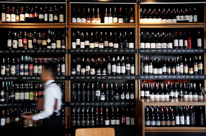 FILE PHOTO: A server passes a wine rack at the Cork & Screw restaurant in Jakarta