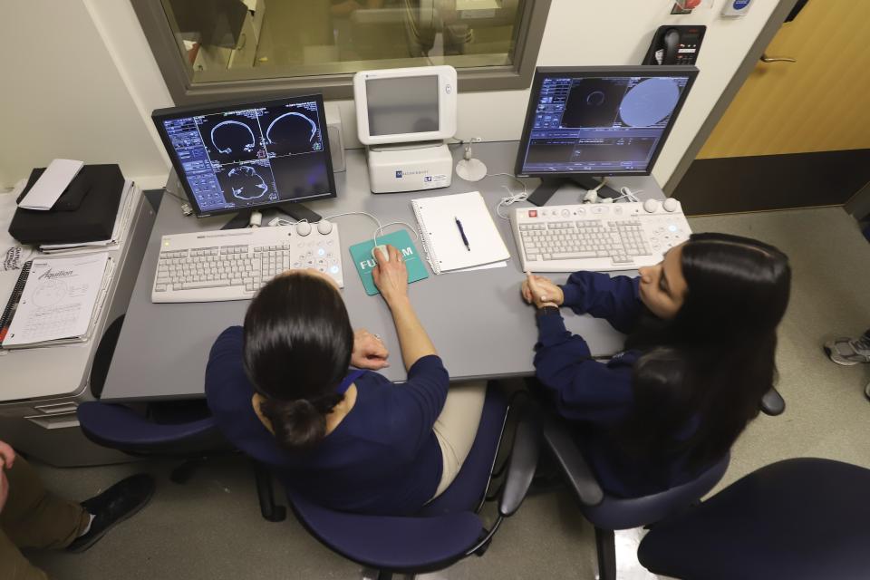 Tania Grgurich, left, clinical associate professor of diagnostic imaging at Quinnipiac University, sits with Ariana DiPietrantonio, a senior radiology student, at Quinnipiac University's Center for Medicine, Nursing and Health Sciences, Friday, Jan. 3, 2020, in North Haven, Conn. The university laboratory began tests Friday on skeletal remains found beneath an 18th century home to help identify the three people believed to be soldiers killed during the Revolutionary War. (AP Photo/Chris Ehrmann)