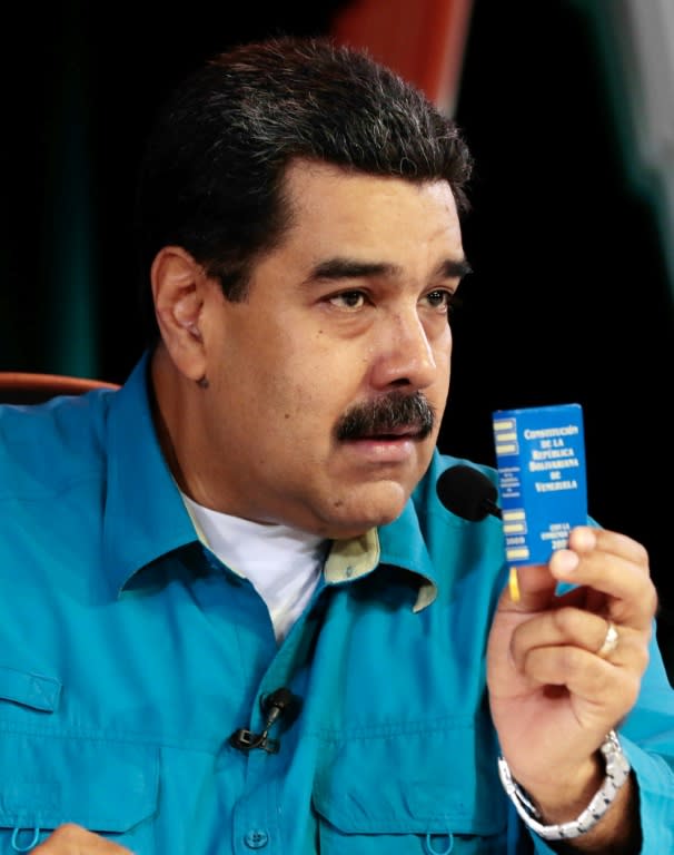 Venezuelan President Nicolas Maduro holds the constitution during a TV program in Caracas, on April 30, 2017