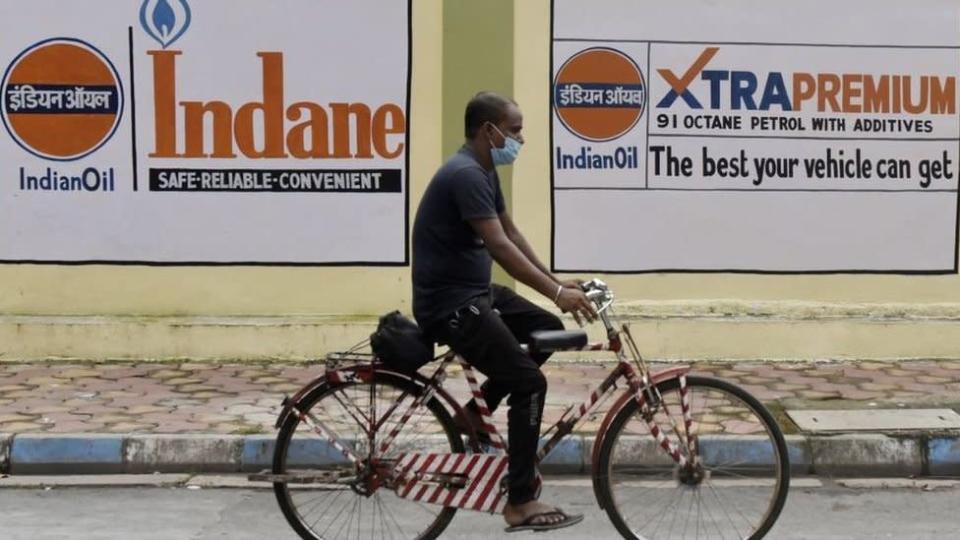 A man on a bicycle passes a petrol station in Kolkata as oil prices rise
