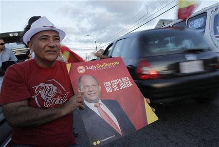 A supporter holds a poster of Luis Guillermo Solis, presidential candidate of the Citizens' Action Party (PAC), as he stands on a street during the presidential election run-off in San Jose April 6, 2014. REUTERS/Juan Carlos Ulate