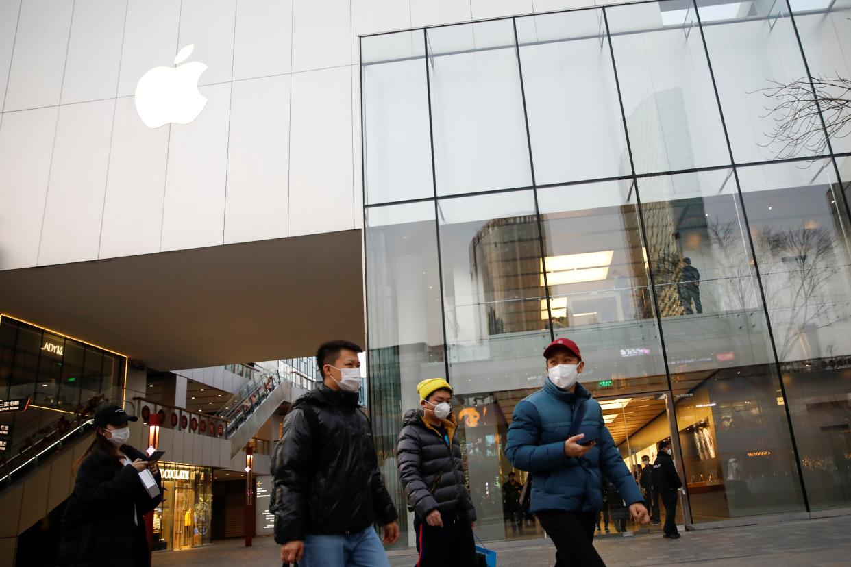 People wearing face masks walk in front of an Apple store at a shopping mall, in Beijing amid the coronavirus outbreak REUTERS/Carlos Garcia Rawlins