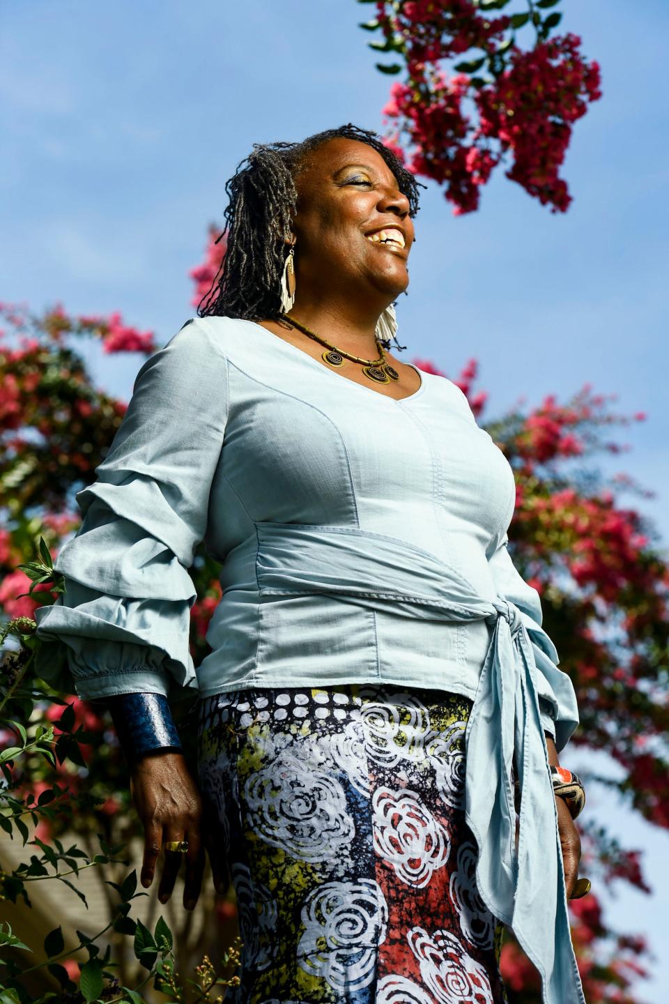 Glenis Redmond, Greenville's first poet laureate, laughs as she poses for a portrait in her front yard on Wednesday, Aug. 9, 2023.