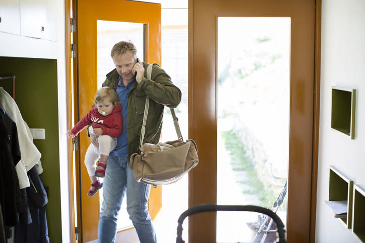 A father holding his baby and their diaper bag