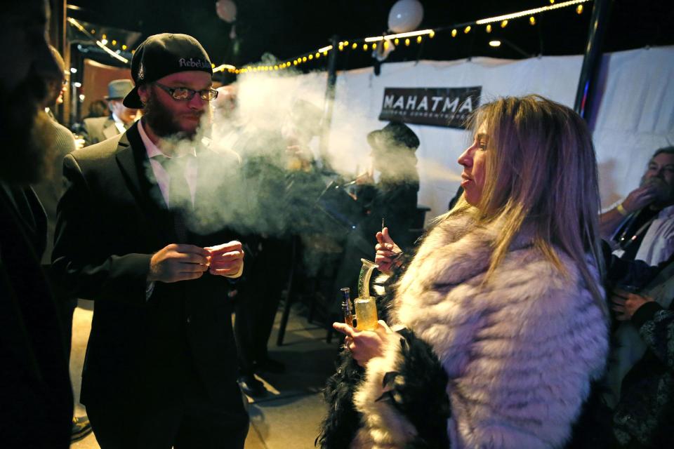 FILE - In this Dec. 31, 2013 file photo, partygoers smoke marijuana during a Prohibition-era themed New Year's Eve invite-only party celebrating the start of retail pot sales, at a bar in Denver. Colorado is on the brink of becoming the first state with licensed pot clubs. Denver officials are working on regulations to open a one-year pilot of bring-your-own marijuana clubs. (AP Photo/Brennan Linsley, File)