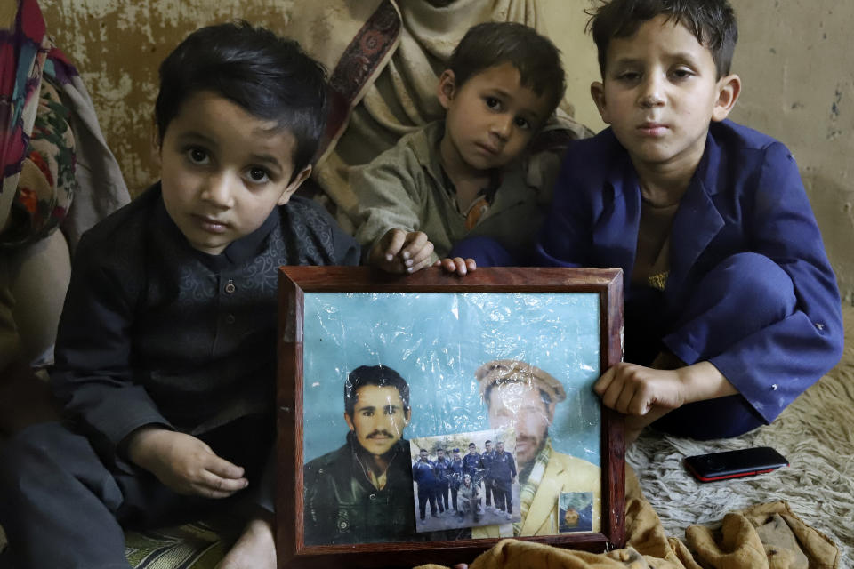 Children of Mohammed Hassan, a Pakistani porter who died on July 27 during a summit of K2, hold a portrait of their father and grandfather at his home in Tasar, a village in the Shigar district in the Gilgit-Baltistan region of northern Pakistan, Saturday, Aug. 12, 2023. An investigation has been launched into the death of a Hassan near the peak of the world's most treacherous mountain, a Pakistani mountaineer said Saturday, following allegations that dozens of climbers eager to reach the summit had walked past the man after he was gravely injured in a fall. (AP Photo/M.H. Balti)