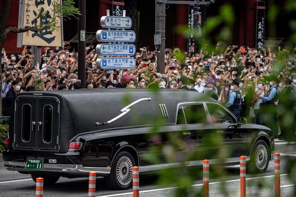 People watch the hearse transporting the body of late former Japanese prime minister Shinzo Abe as it leaves Zojoji Temple in Tokyo