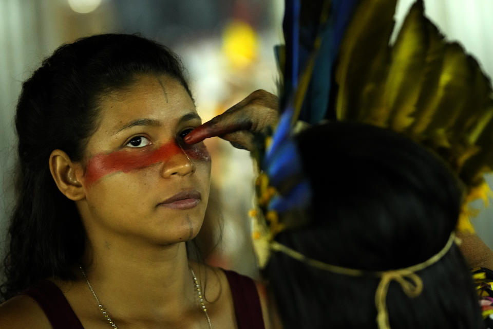 An Indigenous model paints the faces of other models during a fashion event, as part of the Third March of Indigenous Women, to claim women's rights and the demarcation of Indigenous lands, in Brasilia, Brazil, Tuesday, Sept. 12, 2023. (AP Photo/Eraldo Peres)