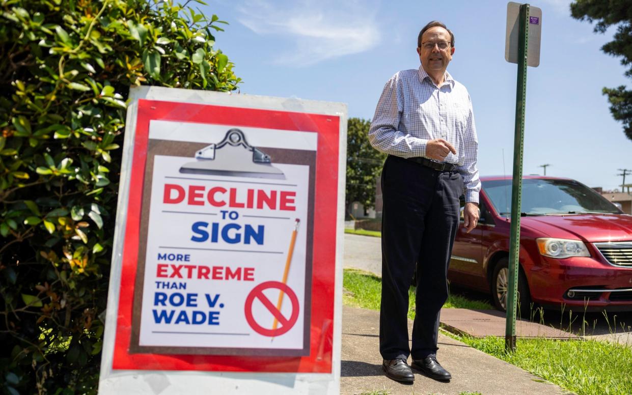 Jerry Cox stood next to a sign that says decline to sign