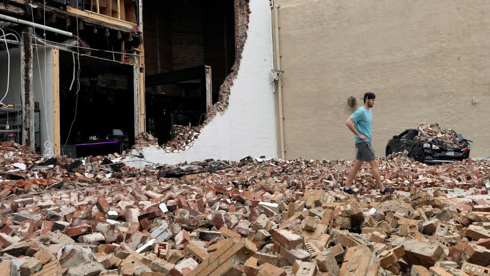 A man walks through fallen bricks from a damaged building in the aftermath of a severe thunderstorm in Houston on Friday. - David J. Phillip/AP