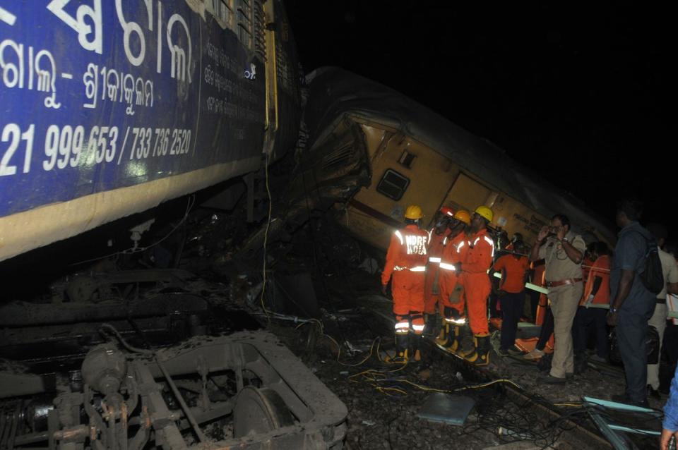 Rescuers and others stand after two passenger trains collided in Vizianagaram district (AP)